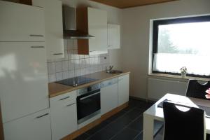 uma cozinha com armários brancos, um lavatório e uma janela em Appartement 2 Schlafzimmer, Terrasse, Hund, Kamin em Bodenwerder