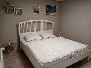 a white bed in a bedroom with pictures on the wall at Appartement 2 Schlafzimmer, Terrasse, Hund, Kamin in Bodenwerder