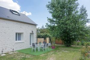 un patio con mesa, sillas y un árbol en Maison/appartement avec jardin, en Saint-Denis-en-Val