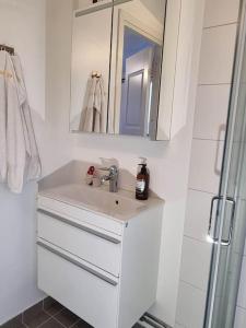 ein weißes Badezimmer mit einem Waschbecken und einem Spiegel in der Unterkunft Villa Stockholms skärgård 30 min från Stockholm centralt in Tyresö