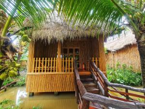 een kleine hut met een rieten dak en een trap daarheen bij Bamboo Eco Village in Can Tho