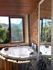 a bathroom with two large windows and a bath tub at Casa da Pedra Serrinha in Resende