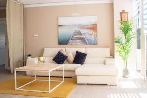 a living room with a white couch and a table at Apartamento con sol de paz in Torremolinos