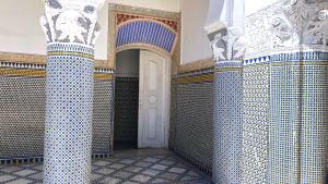 um quarto com paredes de azulejos azuis e brancos e uma porta branca em Youssef em Fez