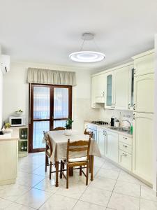 a kitchen with white cabinets and a table with chairs at La Casetta in Folignano