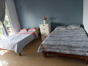 sypialnia z 2 łóżkami i komodą z kwiatami w obiekcie Villa Margaritas w mieście Bacalar
