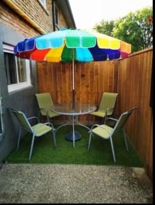 a table and chairs under a colorful umbrella at Patio privé, hébergement équipé et spacieux. in Hamilton