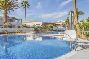 un hotel con una piscina con una silla blanca y palmeras en Bella Vista, Golf del Sur, en San Miguel de Abona