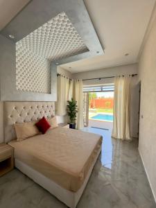um quarto com uma cama grande e uma janela grande em Villa hidaya sans vis à vis em Marrakech