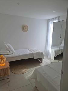 Una habitación blanca con una cama y un espejo. en L ' EDEN, en Saint-Tropez
