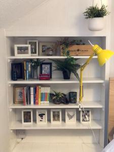 a white book shelf with books and a lamp at Cheerful 4 bedroom townhouse, side street parking in Belfast