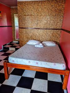 een bed in een kamer met een geruite vloer bij Pousada Aguiar in Rio Preto Da Eva
