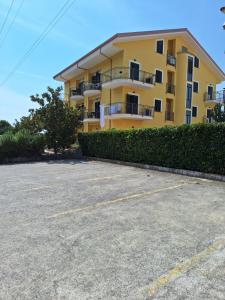 ein gelbes Apartmenthaus mit Parkplatz in der Unterkunft Casalbergo Curciosrl in Belmonte Calabro