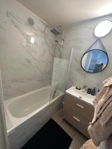 a bathroom with a tub and a sink and a mirror at Le venizio Sète in Sète