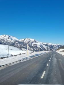 an empty highway with snow covered mountains in the background at Casa Rural Maria de Isidro in Caboalles de Arriba