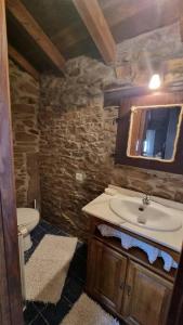a stone bathroom with a sink and a toilet at Casa Rural Maria de Isidro in Caboalles de Arriba