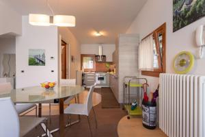 eine Küche und ein Esszimmer mit einem Glastisch und weißen Stühlen in der Unterkunft Martina's Amazing View in Perledo