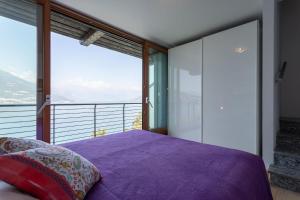 Schlafzimmer mit einem lila Bett und großen Fenstern in der Unterkunft Martina's Amazing View in Perledo