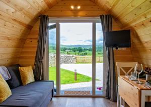 a living room with a couch and a large window at Malhamdale Glamping in Skipton