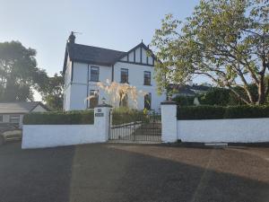 a white house with a gate in front of it at The Villa Farmhouse in Cushendun