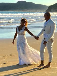 a bride and groom walking on the beach at Villa Lulu Geribá in Búzios