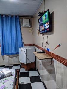 Habitación con TV en la pared y mesa. en Pousada Aguiar, en Rio Preto Da Eva