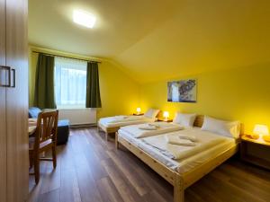 two beds in a room with yellow walls at Írisz Panzió in Budapest