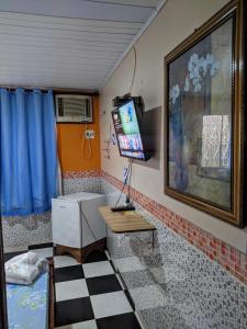 Habitación con escritorio y TV en la pared. en Pousada Aguiar en Rio Preto Da Eva