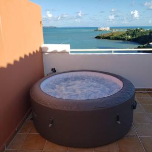 a large tub sitting on a balcony with a view of the ocean at Boricua Realty VIP Luxury Ocean Front Penthouse 3 Bedrooms 3 Bathrooms 2 Levels in Fajardo