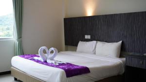 a hotel room with a bed with a bow on it at Salsa Resort Langkawi By Casa Loma in Pantai Cenang