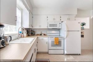 a kitchen with white cabinets and a white refrigerator at In the Center of Gulfport, Min Away From the Beach! in St Petersburg