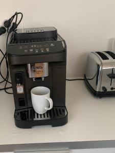 een koffiezetapparaat met een kopje op een aanrecht bij bel appartement proche centre parking gratuit in Straatsburg