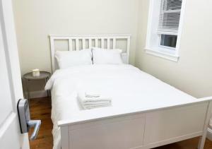 Cama blanca en habitación con ventana en Newly Renovated Guest Rooms near Transportation, en Filadelfia