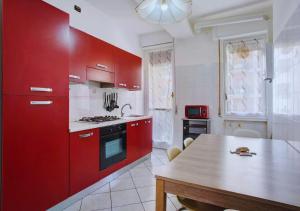 una cucina con armadi rossi e tavolo in legno di Appartamento Tre Locali Accogliente A Nova Milanese ,Vicinanza A Milano e Stadio Monza a Nova Milanese