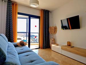 a living room with a blue couch and a sliding glass door at Las Rocas by the Ocean, Wifi and Sea View in Los Abrigos