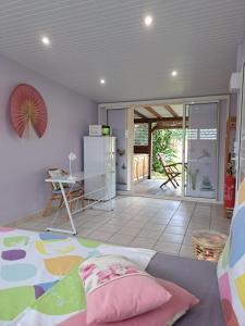 a room with a bed and a table and a refrigerator at Studio Perle de Zanzibar Trois-Ilets in Les Trois-Îlets