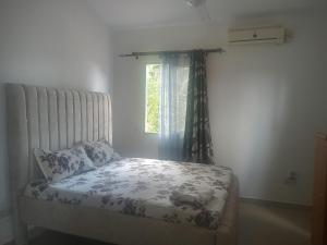 een bed in een kamer met een raam en een sprei bij Vipingo royal homes in Kilifi