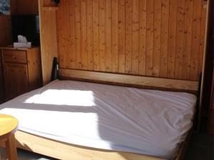 łóżko w pokoju z drewnianą ścianą w obiekcie Appartement Le Grand-Bornand, 1 pièce, 4 personnes - FR-1-241-24 w mieście Le Grand-Bornand
