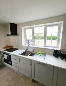 a kitchen with a sink and two windows in it at Granary Villa in Kidderminster