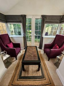 a living room with two purple chairs and a coffee table at Granary Villa in Kidderminster