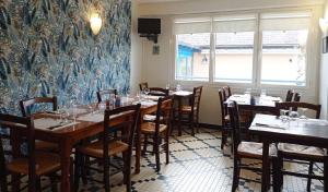 a dining room with tables and chairs and a wall mural at Auberge Armoricaine in Louisfert