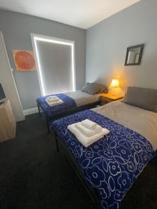 een slaapkamer met 2 bedden en handdoeken bij Cosy and Comfortable Newly Refurbished Family Home in Hull