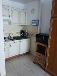 a kitchen with white cabinets and a sink and a microwave at saint jean de mont, Superbe studio balcon face mer in Saint-Jean-de-Monts +11 photos