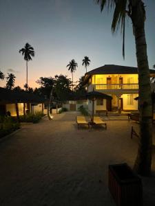 a building with benches and palm trees at sunset at Mem Luxury Apartments and Hotel in Paje