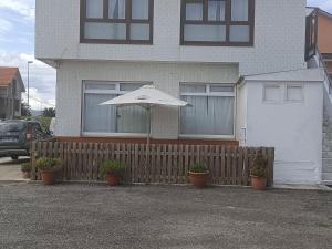 casa sisargas في لا كورونيا: وجود مظلة بيضاء تجلس أمام المنزل