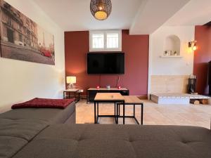 a living room with a couch and a flat screen tv at LA MAISON DES ARUMS-WIFi-JARDIN PRIVE-PROPERTY RENTAL NM in Trélissac