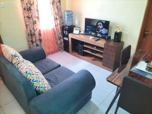 a living room with a blue couch and a television at Arunga's Homely Kakamega Stay in Kakamega