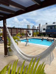 a hammock in a swimming pool with people playing at Marinas Flat 116 in João Pessoa