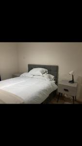 - une chambre avec un lit blanc et une lampe sur une table de chevet dans l'établissement Cosy central London flat Trafalgar Square, à Londres