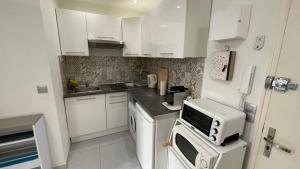 eine kleine Küche mit weißen Schränken und einer Mikrowelle in der Unterkunft Studio rue piétonne proche plage in Menton